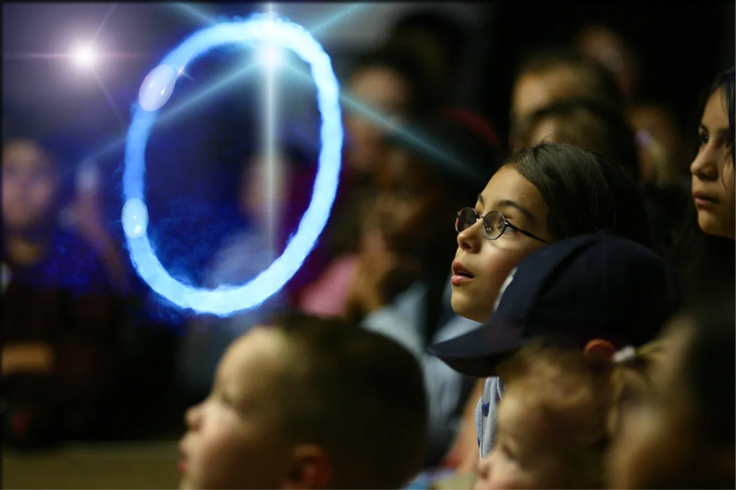 Young audience members watching a glowing bubble ring